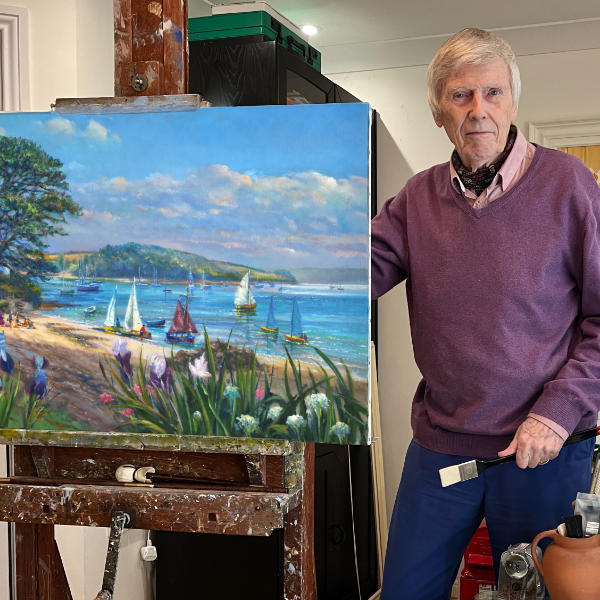 Cornish artist Ted Dyer standing in his Falmouth studio with one of his oil paintings oil on his painting easel