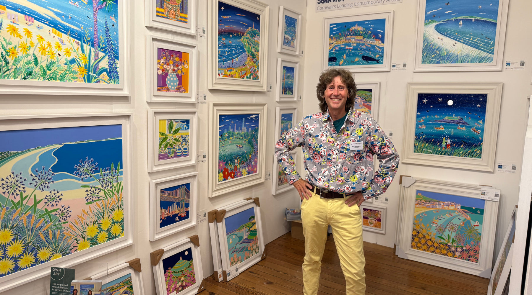 Artist John Dyer standing with paintings available from The John Dyer Gallery