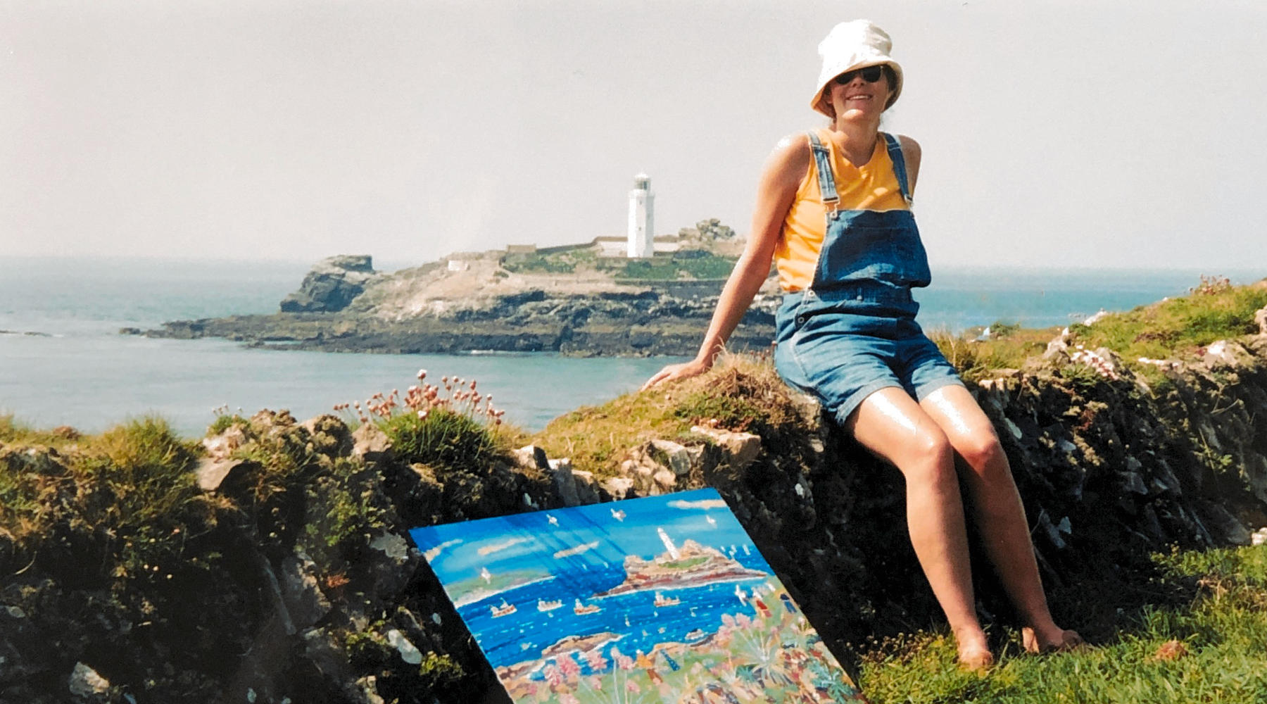 English artist Joanne Short seen at Godrevy Lighthouse in Cornwall with a John Dyer painting