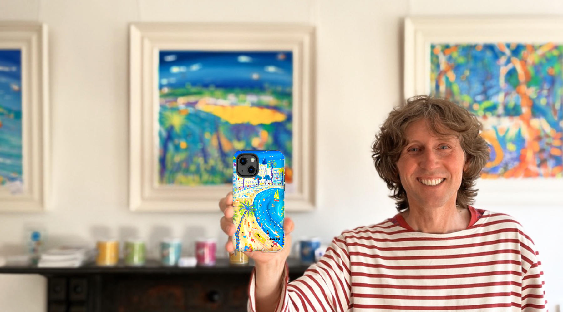 Artist John Dyer holding an iPhone with one of his paintings of Cannes on the phone case