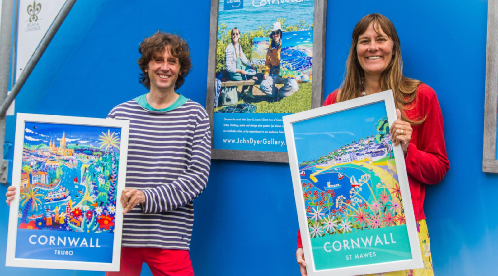 Local artists John Dyer and Joanne Short holding examples of their local prints - pictured onboard the King Harry Ferry in Cornwall