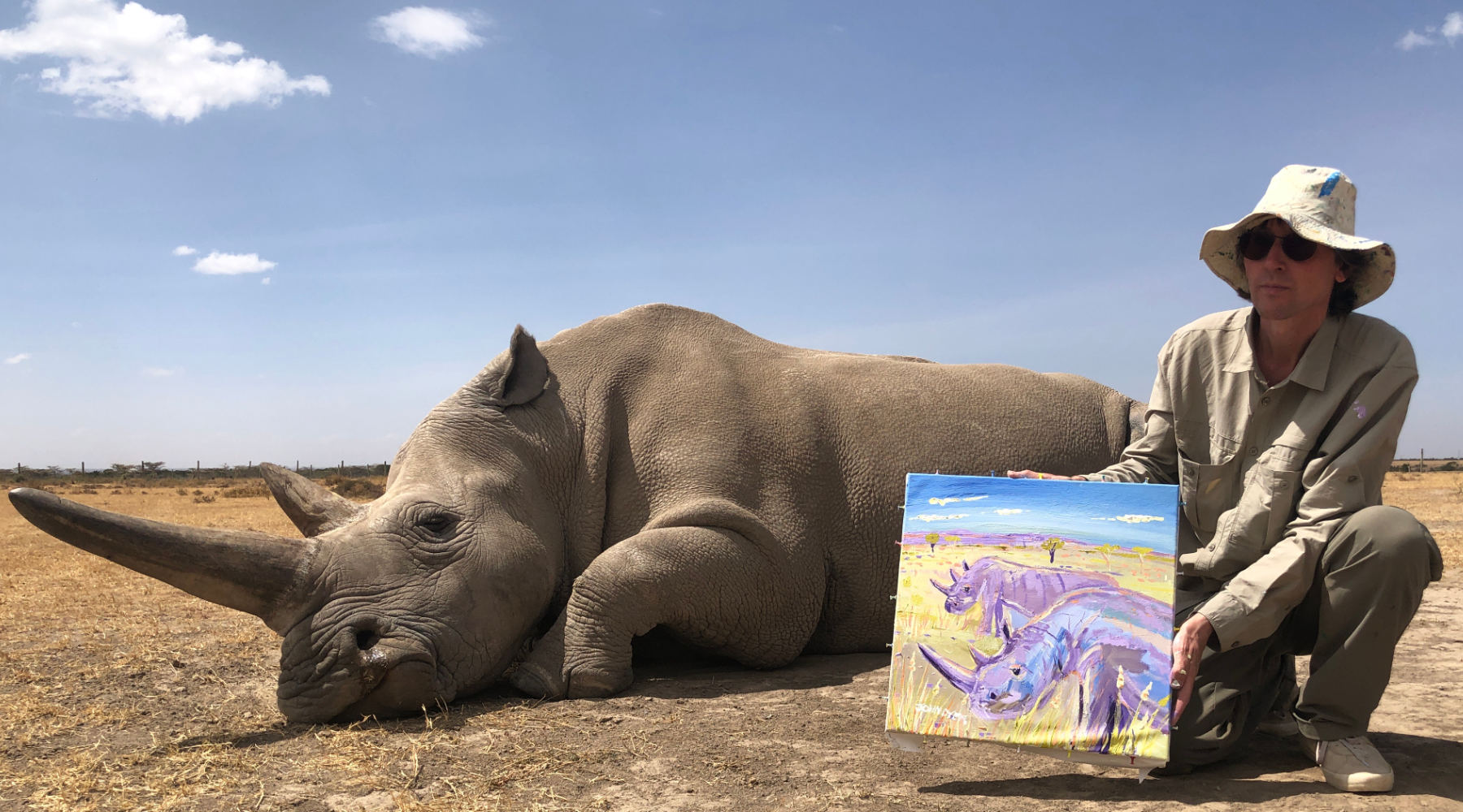 British artist pictured with one of the last two Northern White Rhino at OlPejeta conservancy in Kenya, Africa with a painting he created from life with the animals.