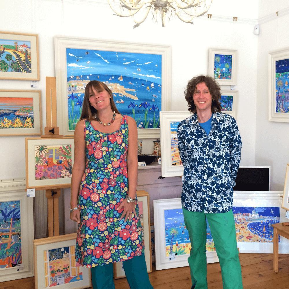 Cornish artists Joanne Short and John Dyer standing in The John Dyer Gallery in Cornwall surrounded by original paintings of Cornwall