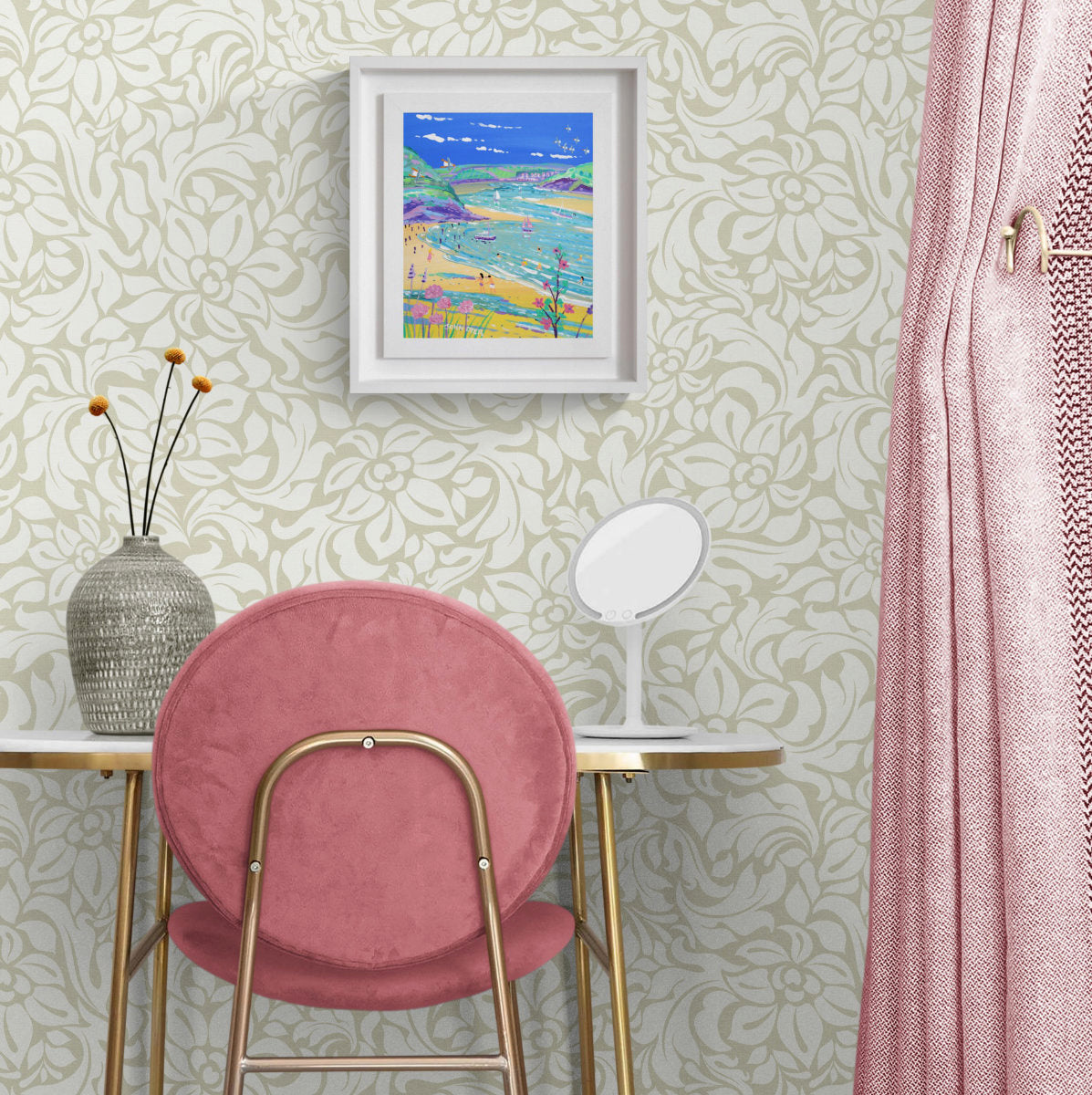 A framed colourful beach painting hangs on a patterned wallpaper wall above a pink velvet chair and a white table with a mirror. A pink curtain is visible on the right. 'Watching the Tide come in, Daymer Bay, Rock', 12 x10 inches acrylic on canvas by Cornish Artist John Dyer