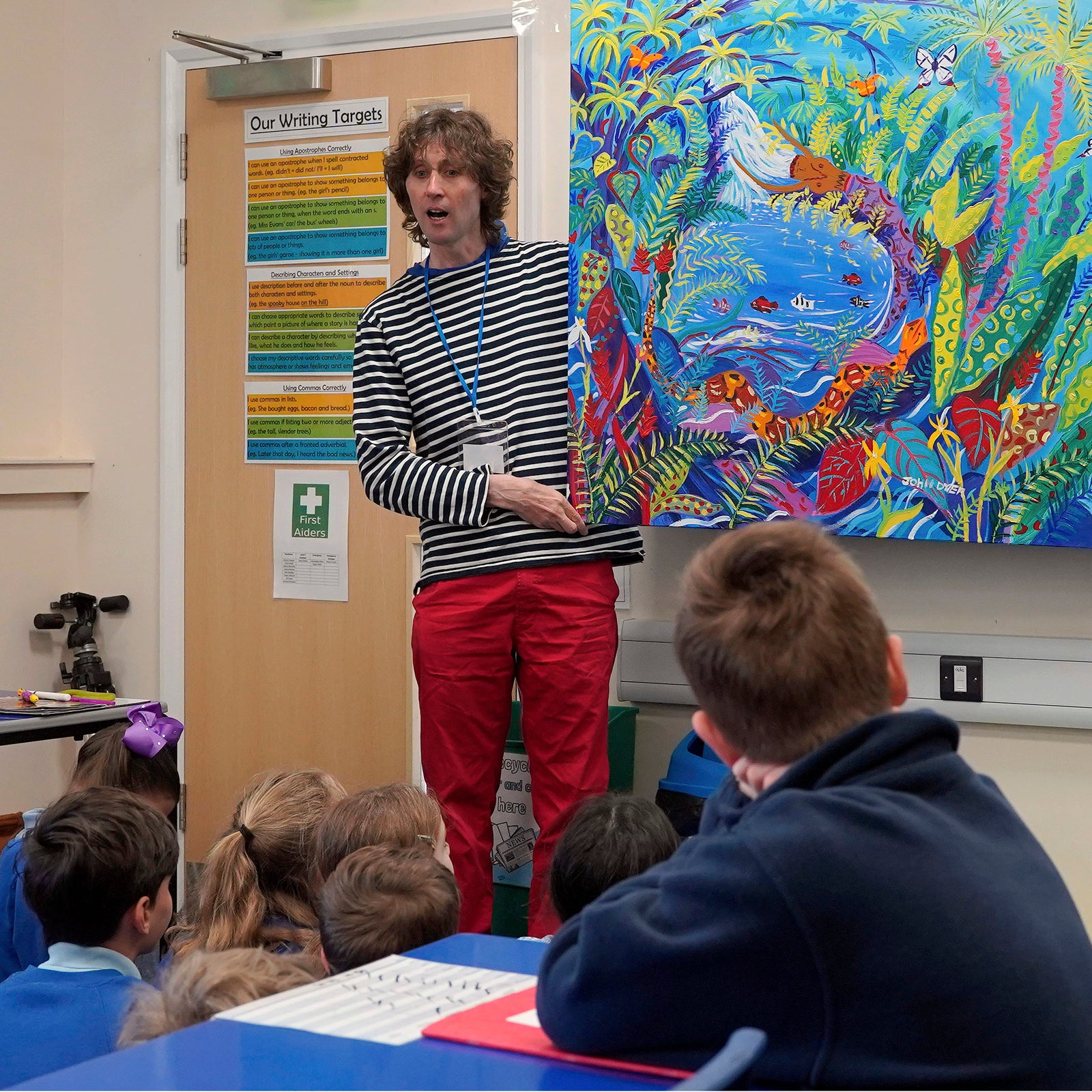 Artist John Dyer in a British school talking about his Amazon rainforest painting during an art workshop.