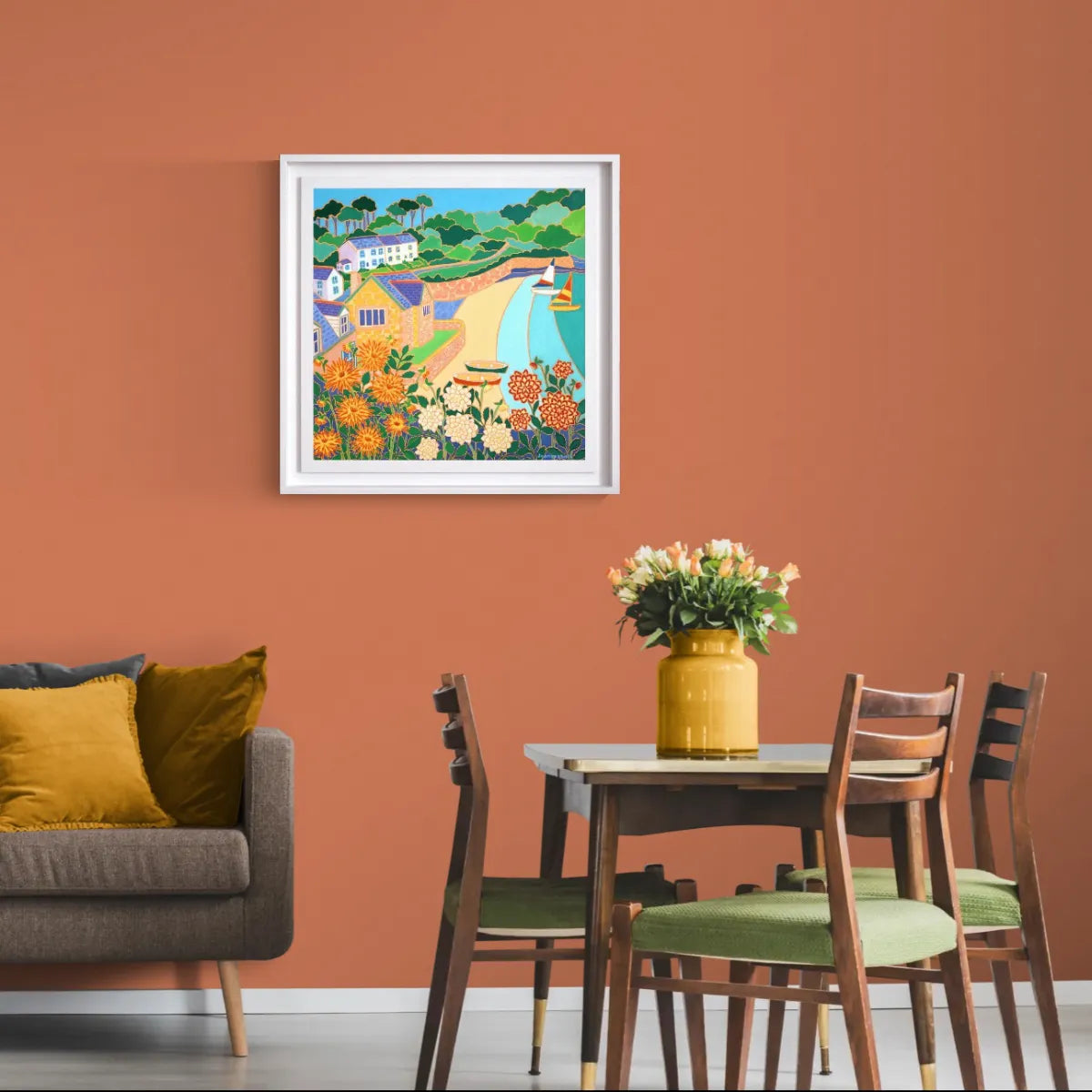 Dining room with a colorful painting on the wall, a table with a vase of flowers, and a sofa. 'Dahlias and Dinghies, Durgan’. 24x24 inches oil on canvas. Original Painting of Cornwall by Cornish Artist Joanne Short