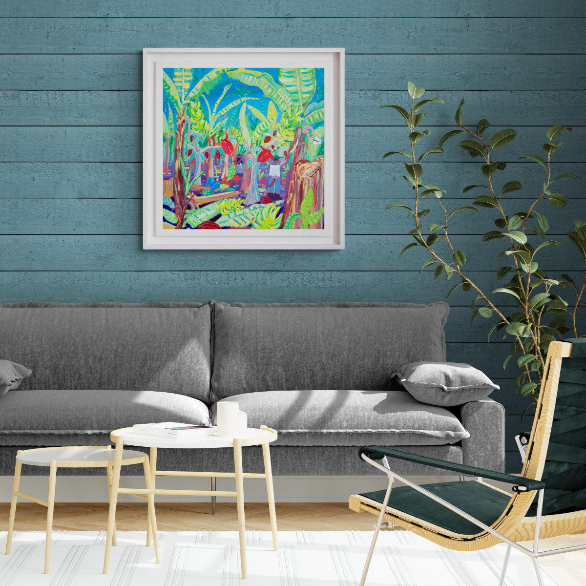 Living room with gray sofa, colorful painting, and plant against a blue wall. 'Intercropping and Chopping, Costa Rica Bananas and Chocolate Trees', 24x24 inches acrylic on canvas. Tropical Costa Rica Painting by British Artist John Dyer0