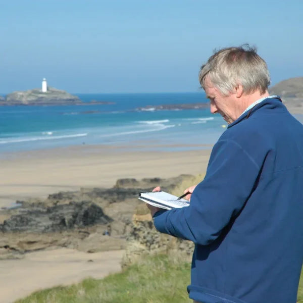 Cornish artist Ted Dyer sketching Godrevy Lighthouse from Gwithian Sands in Cornwall.