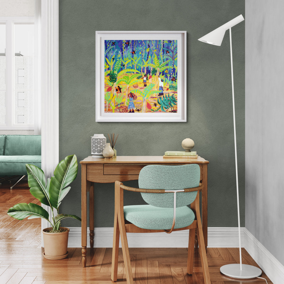 Home office with a desk, chair, and colorful artwork on a green wall. 'Rainforest Banana Bonanza, Costa Rica', 24x24 inches acrylic on canvas. Tropical Costa Rica Painting by British Artist John Dyer