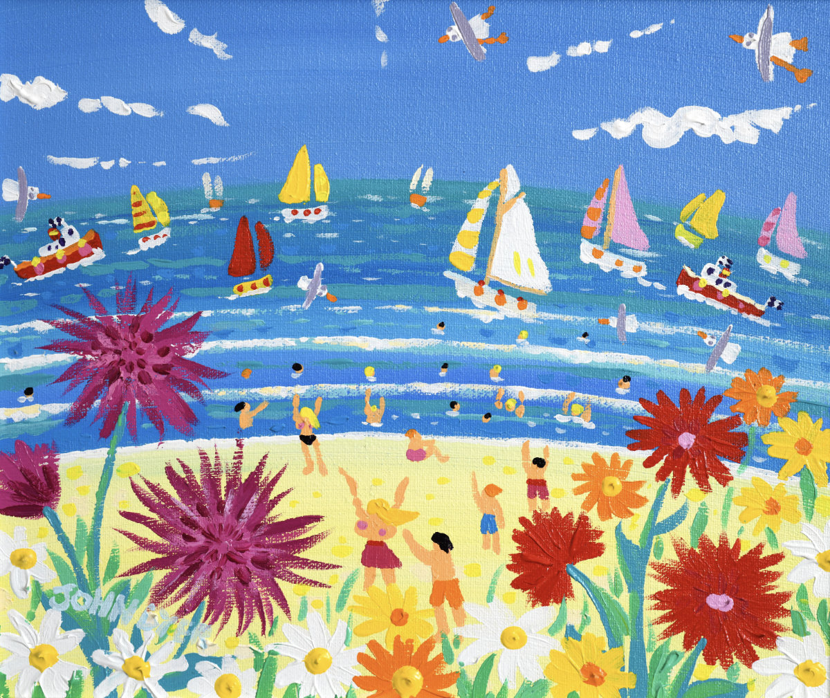 A colorful beach scene painting with sailboats on blue water, small figures of people on the sandy shore, and large flowers in the foreground under a bright blue sky. John Dyer Original Painting. ‘A Burst of Cornish Colour’. 10 x 12 inches acrylic on canvas