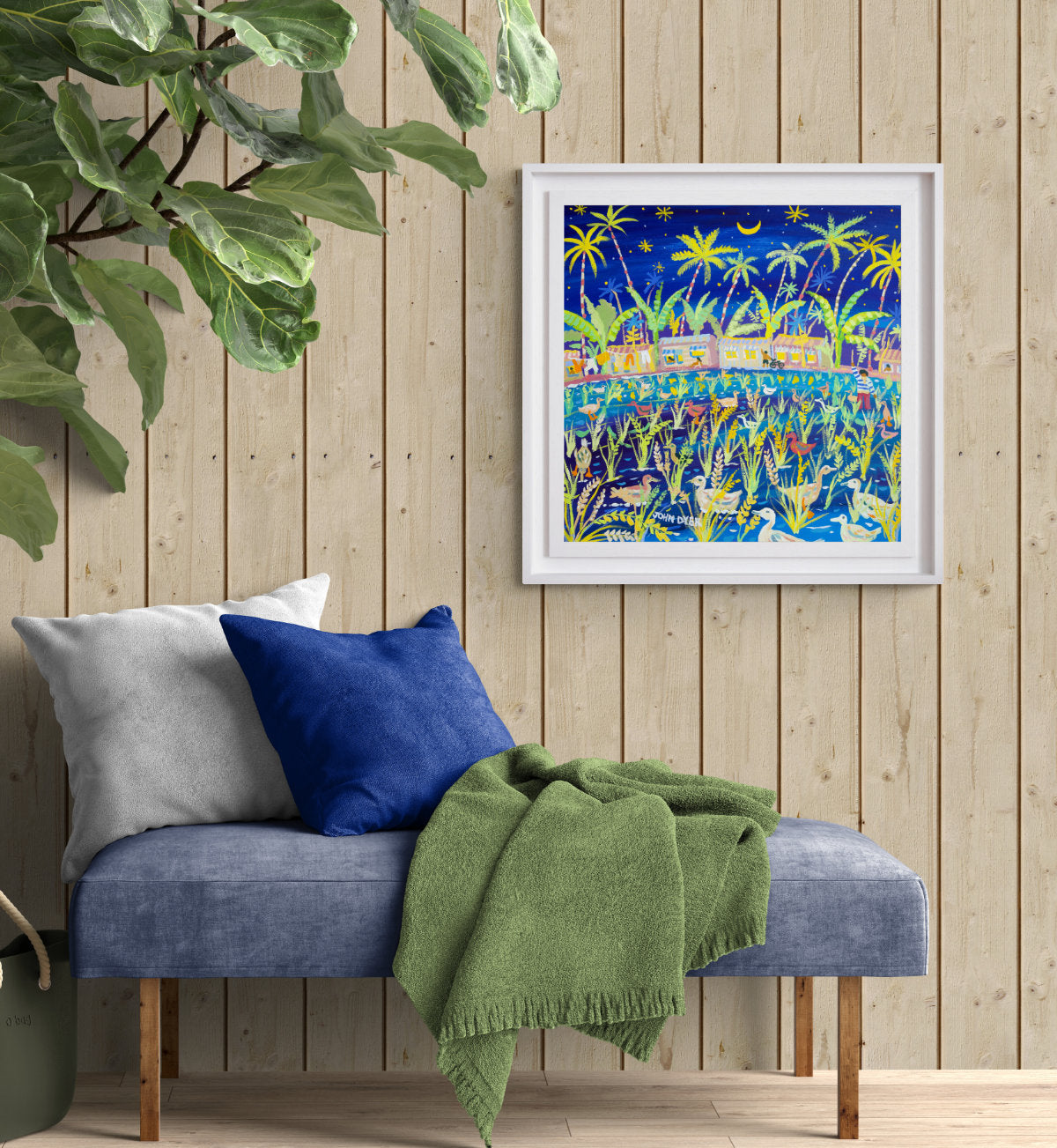 Framed artwork on a wooden wall above a bench with cushions and a blanket. 'Paddy Paddling, the Philippines Rice Harvest'. 24x24 inches acrylic on canvas. Paintings of Philippines by John Dyer from our Online Art Gallery
