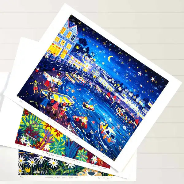 Signed limited edition art prints of Cornwall by John Dyer displayed on a beach hut floor