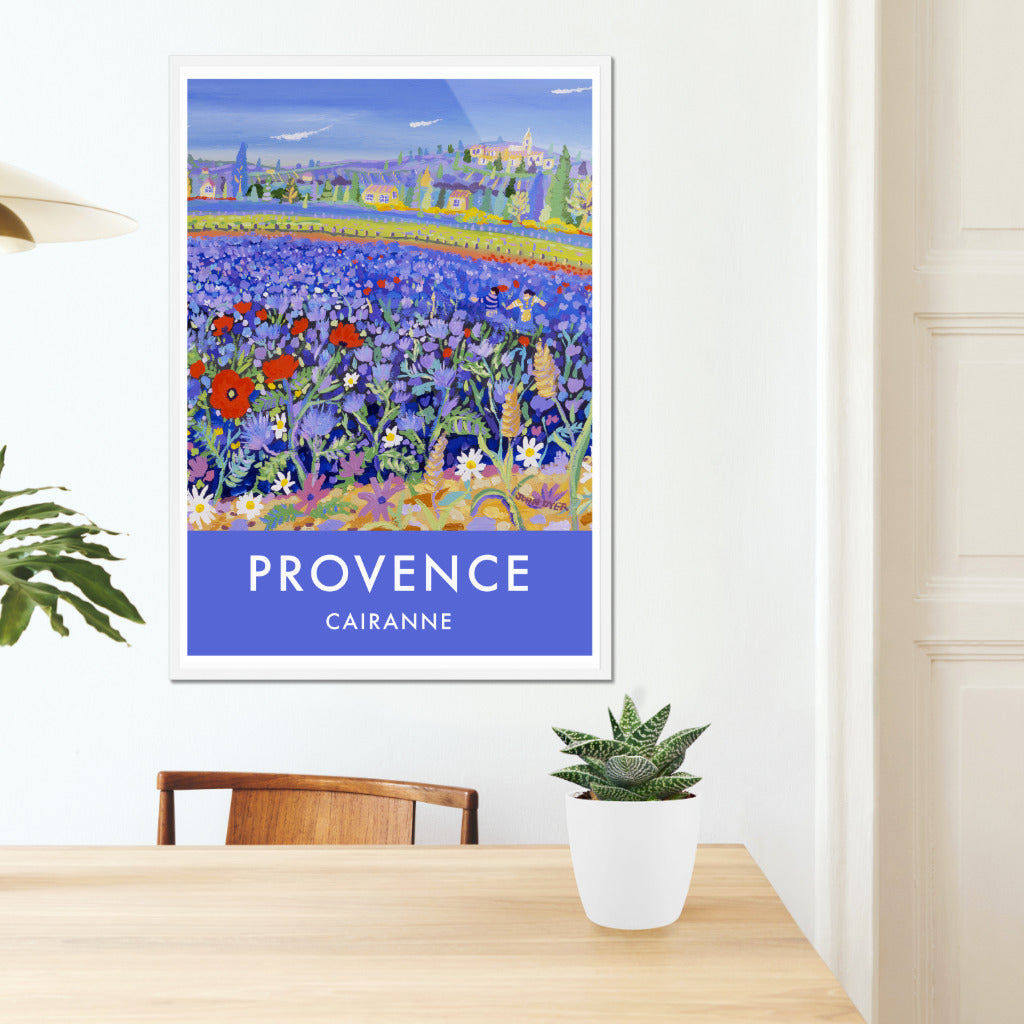 Vintage style travel art poster print of Provence in France featuring the art of John Dyer and the village of Cairanne in the Vaucluse region of Provence in the South of France. John has captured the amazing sight of a field of blue flowers and poppies set against the landscape of Provence and the wine producing village of Cairanne. This travel art poster will look stunning in your home or office and is available unframed or framed and ready to hang on your wall.