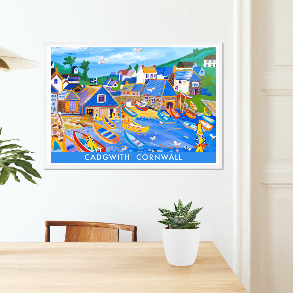 One of John Dyer&#39;s most famous paintings of Cadgwith is now available on this seaside vintage style travel fine art poster print. John&#39;s work is combined with vintage style type &amp; block colour. Fishing boats crowd the beach at Cadgwith Cove on the Lizard in Cornwall. Fishermen catch lobsters and fish and seagulls zoom through the sky. A Cornish flag flies over the boat house. A brilliant art poster of Cornwall that is supplied unframed or framed in a wide variety of sizes.