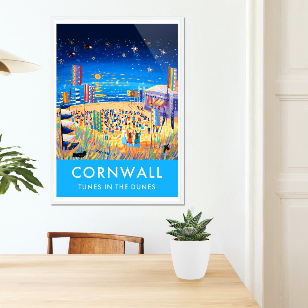 A stunning wall art poster print of the Tunes in the Dunes Music Festival on Perranporth Beach in Cornwall by Cornish artist John Dyer. A night sky full of stars with a glowing North Cornwall sunset lights up the festival flags and crowd. Wild grasses, sand dunes, puffins &amp; seagulls create the essence of Cornwall. A group of teenagers dance in the dunes and colourful lights radiate from the stage. Perfect. Available unframed or framed and ready to hang on your wall.