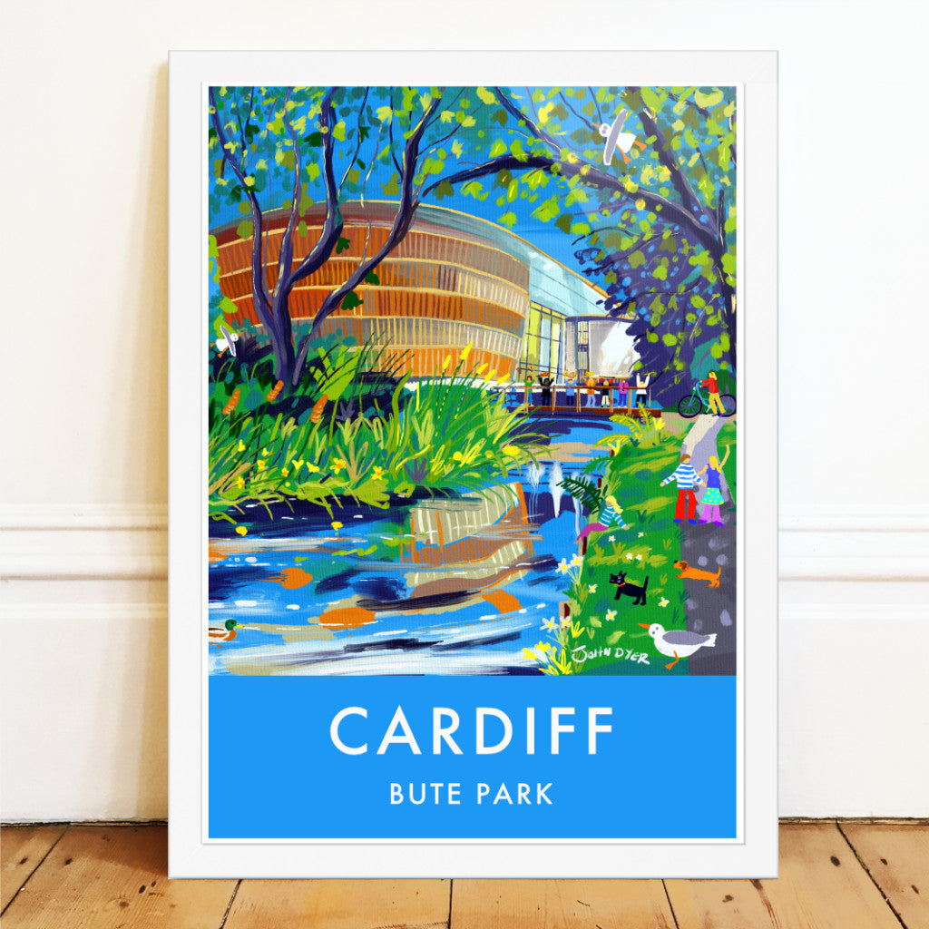This stunning wall art travel poster print by John Dyer features the Royal Welsh College of Music and Drama in Bute Park, Cardiff in Wales. A family stroll through the park under the trees alongside the river. A duck, seagulls, scotty dog and sausage dog look on and on the bridge to the RWCMD musicians wave their musical instruments in the air celebrating their musical lives.